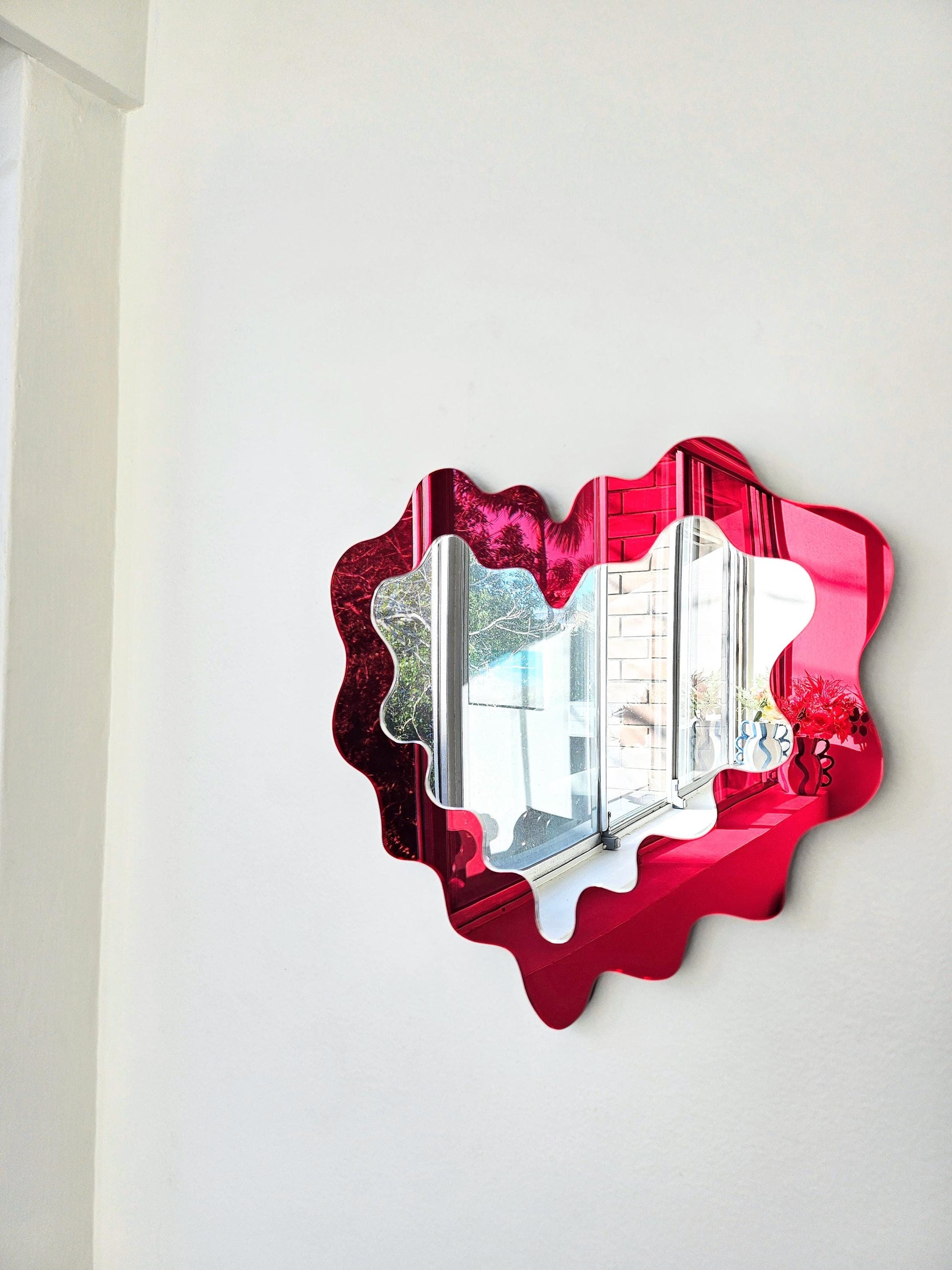 Red wavy mirror on a white wall