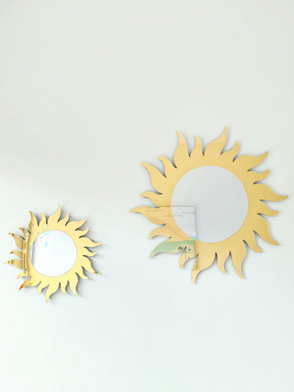 Two sun-shaped wall mirrors on a light gray background